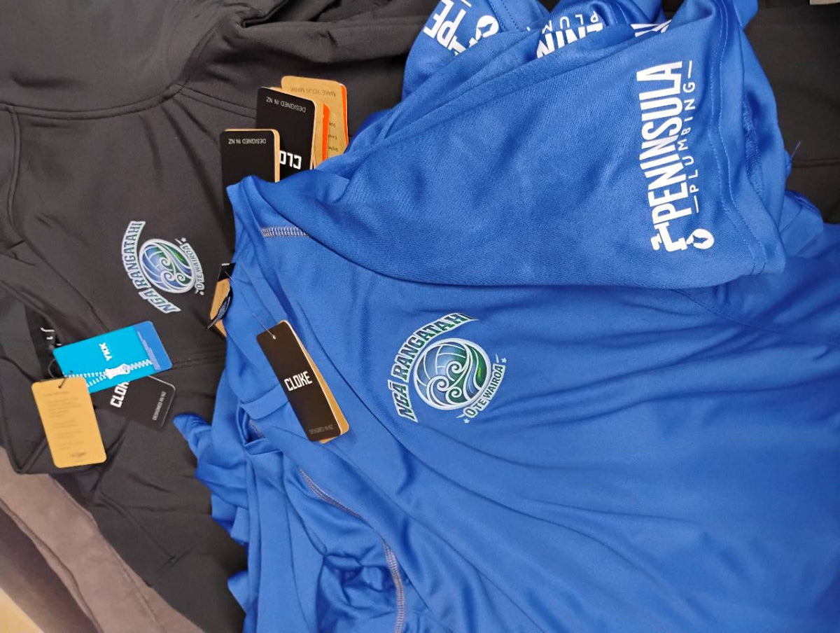 Blue shirts and charcoal zip garments with Ngā Rangatahi O Te Wairoa chest logos and a white Peninsula Plumbing sleeve print.