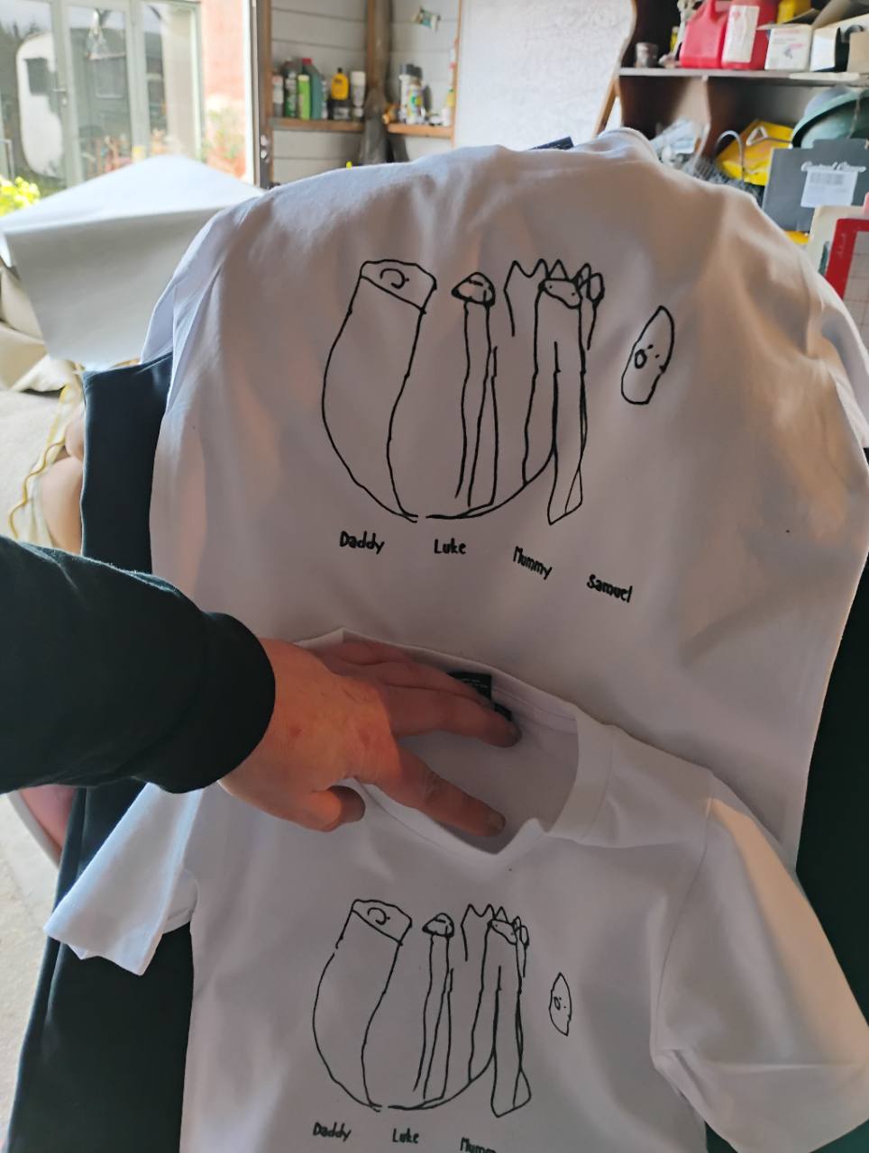 Matching adult and child white T-shirts printed with a family drawing and personalised names.