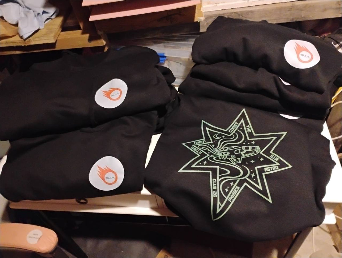 Black garments with orange-and-white circular chest logos and a large green outlined star design.