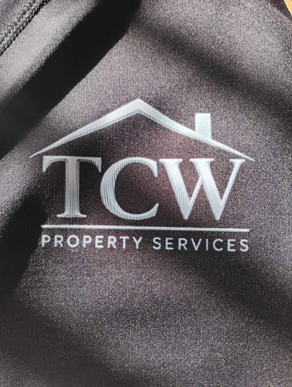 Close-up of a white TCW Property Services logo printed on a black garment.